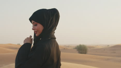 retrato de una hermosa mujer musulmana con hiyab caminando en un desierto ventoso y mirando la cámara 2