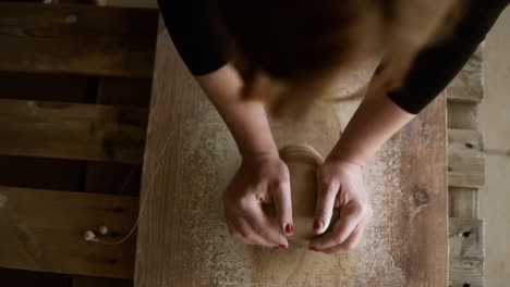 top footage of female hands with beautiful red manicure holding clay and hardly kneading it on a worktop. woman wearing beautiful red manicure