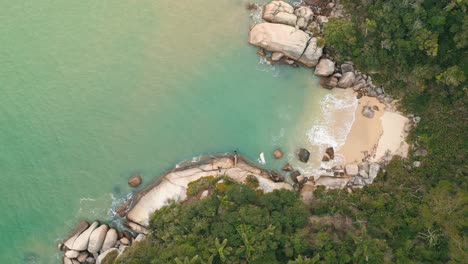 Vista-Aérea-De-Arriba-Hacia-Abajo-De-La-Playa-Tropical-Con-Agua-Clara-Y-Grandes-Rocas-En-Bombinhas,-Santa-Catarina,-Brasil