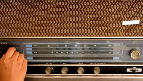 woman hand adjusting the button vintage radio