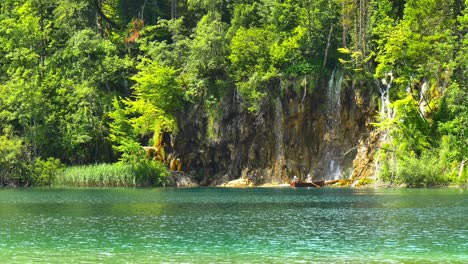 Couple-resting-on-small-boat-next-to-waterfall-in-Plitvice-National-Lake-Park