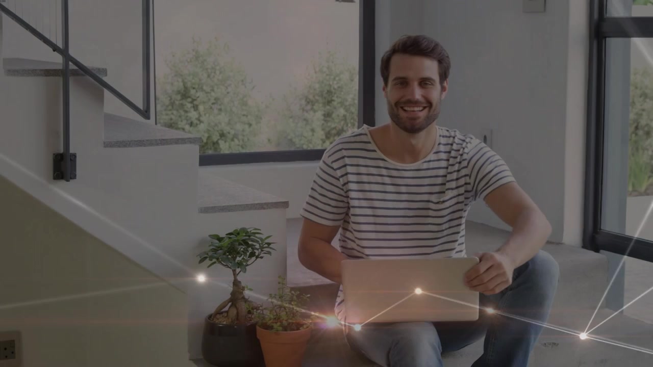 Rete luminosa di connessioni su sfondo del ritratto di un uomo caucasico che usa un laptop a casa.