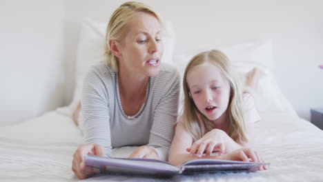 Vista-Frontal-De-Una-Mujer-Caucásica-Leyendo-Un-Cuento-A-Su-Hija-En-La-Cama.