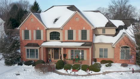 aerial rising establishing shot of upscale brick house in winter snow