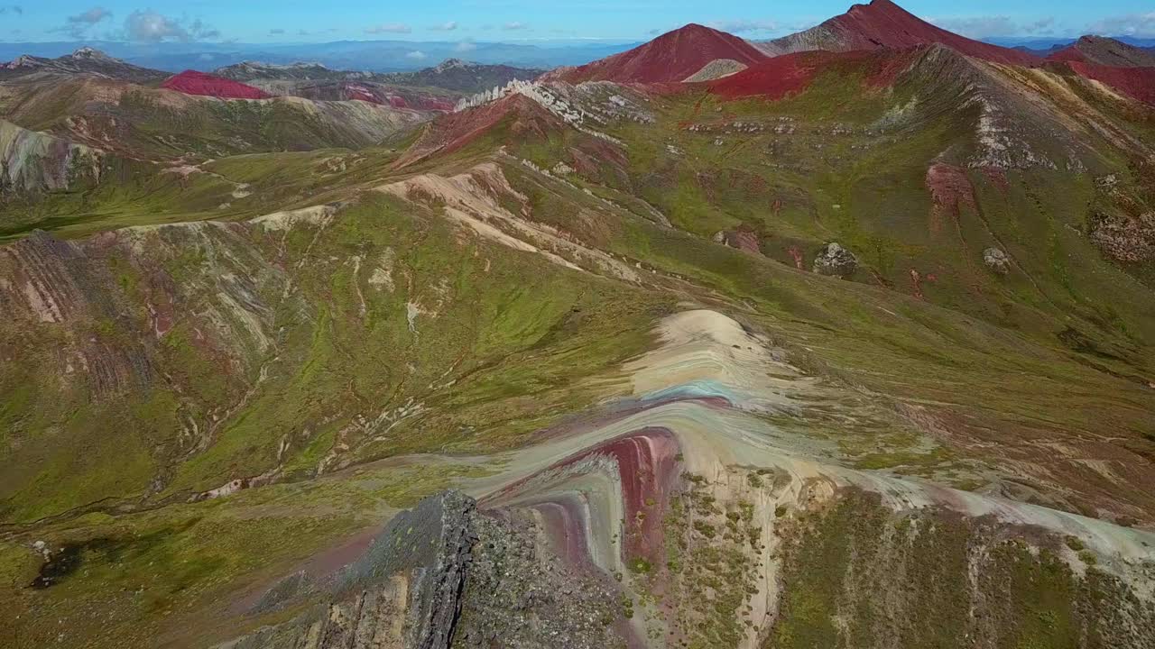 Aerial, drone shot tilting towards the Palcoyo rainbow mountain, in Valle Rojo, on a sunny day, in Andes, Peru, South America
