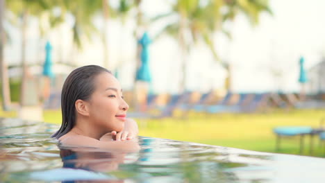 Una-Mujer-Joven-Y-Bonita-Inclina-La-Barbilla-Y-Los-Brazos-A-Lo-Largo-Del-Borde-Infinito-De-La-Piscina-De-Un-Centro-Turístico