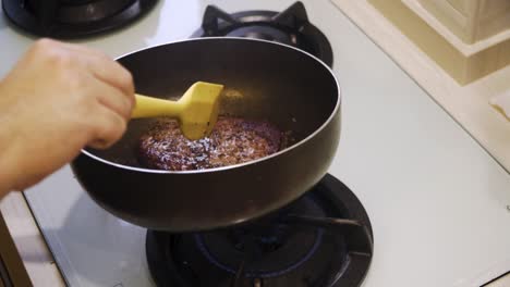 manos rociando bistec wagyu a4 con mantequilla en una sartén