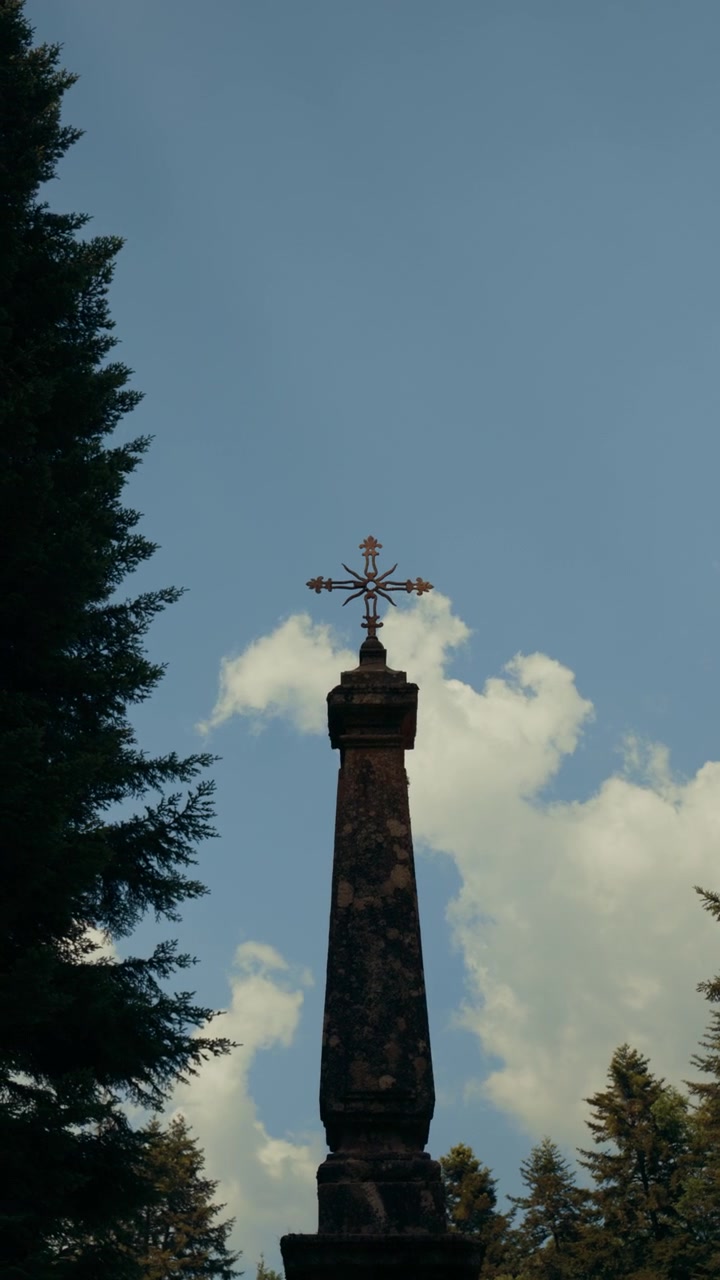 Monumento a croce in pietra contro cielo blu e nuvole