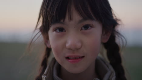 close up portrait little asian girl smiling happy enjoying summer vacation on seaside park sunset real people series