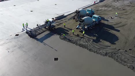 a concrete mixing truck uses the last of its concrete while a screed smooths out the concrete