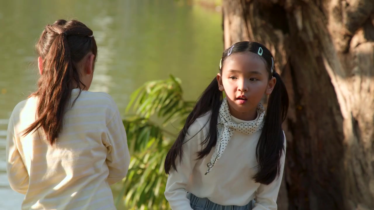 Deux jeunes filles asiatiques se tiennent près d'un lac dans le parc Lumpini, nourrissant des poissons pendant l'heure dorée.