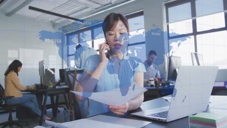 Animation-Einer-Karte-Mit-Zahlen-über-Einer-Asiatischen-Geschäftsfrau,-Die-Den-Bericht-Am-Telefon-Bespricht-Und-Einen-Laptop-Benutzt