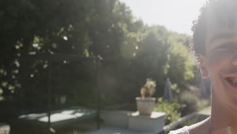 portrait of happy biracial man looking at camera in garden on sunny day