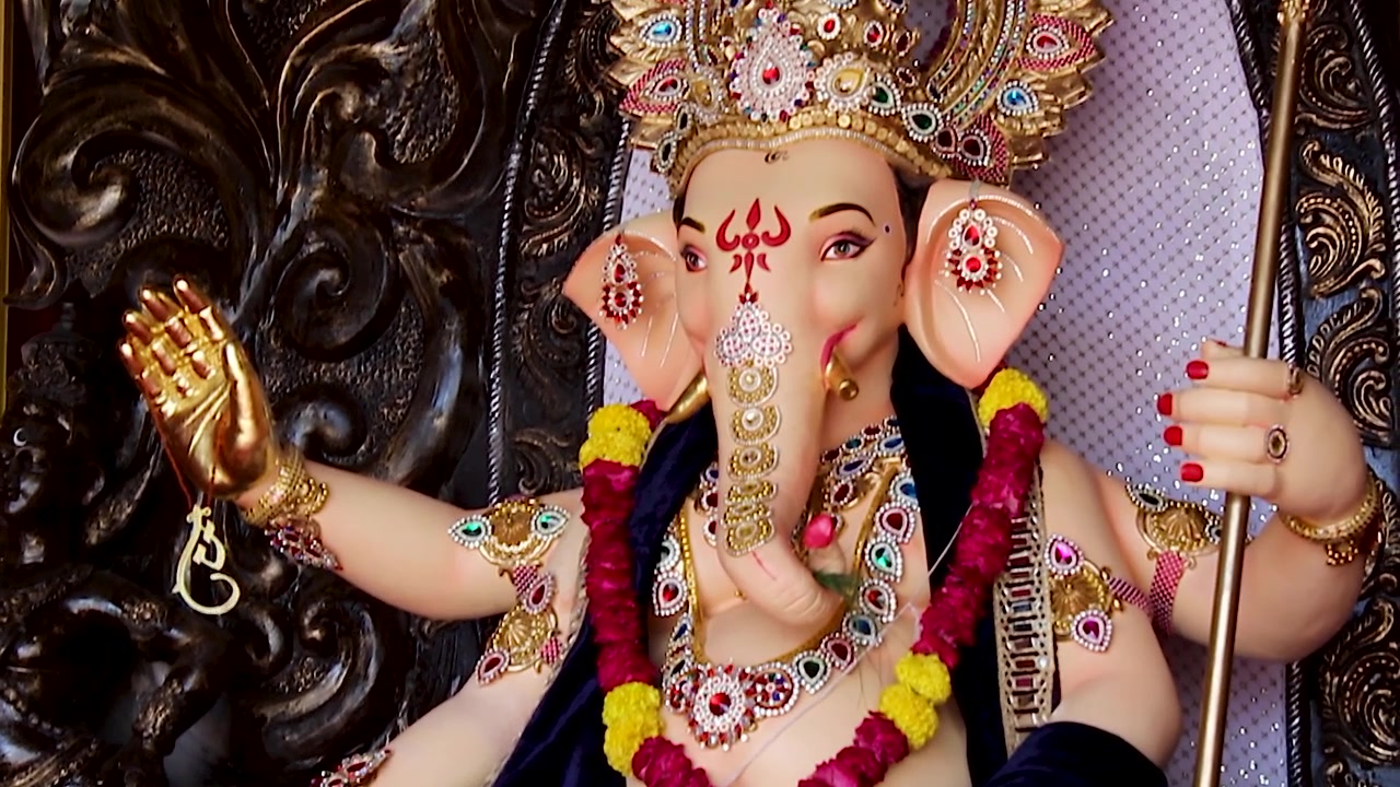 Statua di Ganesha che si inclina rivelando la corona d'oro, la mano benedicente e le ghirlande durante il festival di Ganesh Chaturthi in India