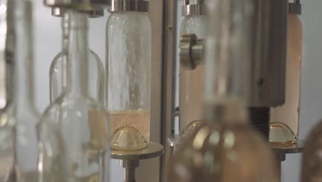 rose wine in glass bottling machine at winery industrial plant