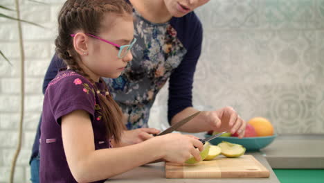 mother teaching daughter to use knife