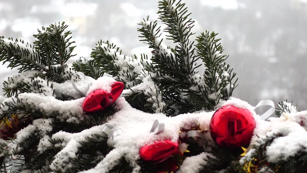 Kar altında oyuncaklarla süslenmiş yılbaşı ağacı dalları.