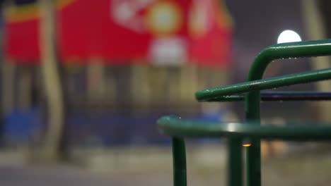un carrusel húmedo girando en el patio de juegos vacío de los niños en el parque de la ciudad en una noche de otoño.