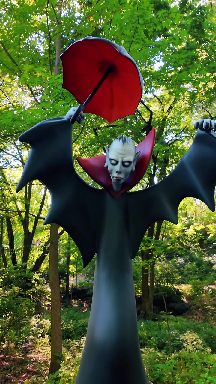 New York, USA, 17 agosto 2025: Scultura di un personaggio vampiro su un piedistallo di pietra in un giardino botanico. Inquadratura completa di una figura di vampiro che tiene un ombrello in piedi su una base di pietra etichettata 'non calpestare'