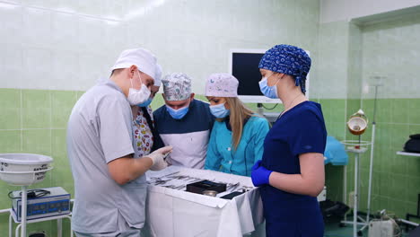 medical students stand around the table with metal tools. teacher demonstrates different instruments used in dentistry.