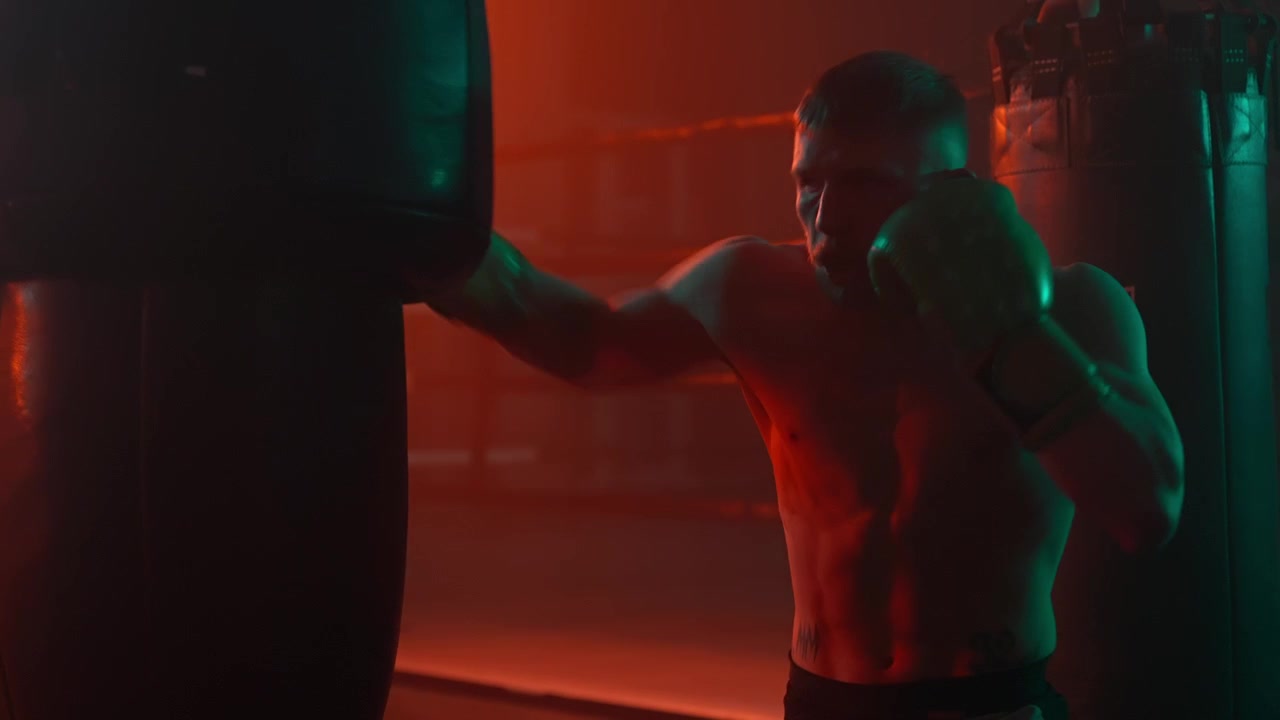 Pugile che si allena con il sacco da boxe in una palestra buia e suggestiva.