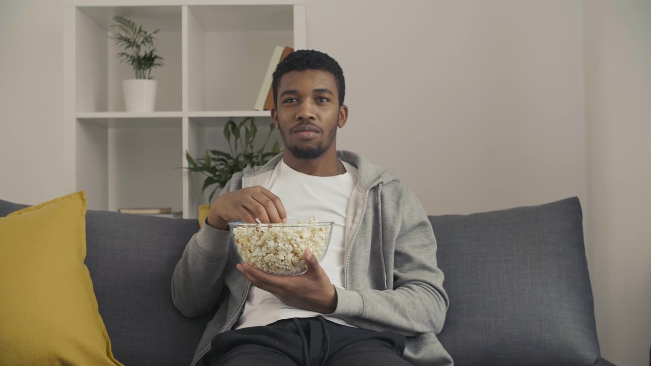 Ung mann ser oppmerksomt på en film og spiser popcorn