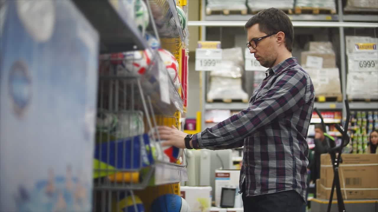 hombre comprando bolas deportivas en una tienda