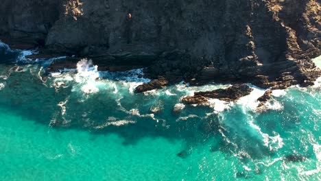 aerial view of waves crashing into ocean rocks