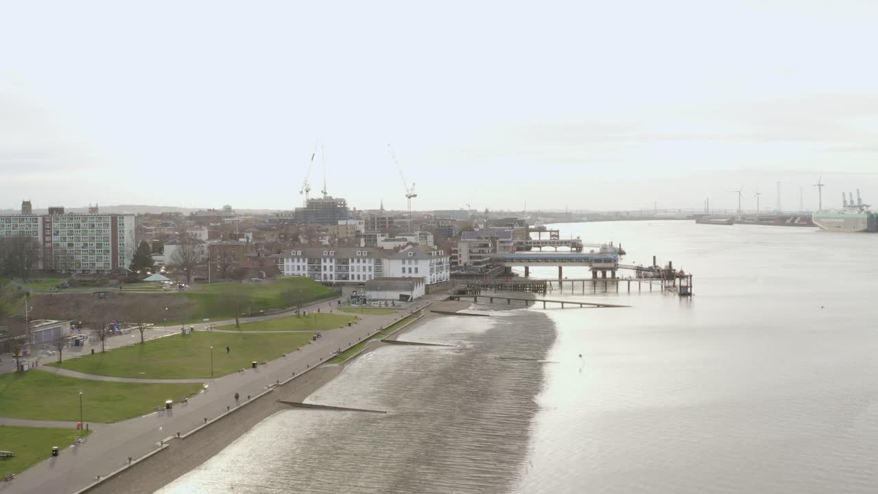 Drone flies low above River Thames near Gravesend showing green banks and docks