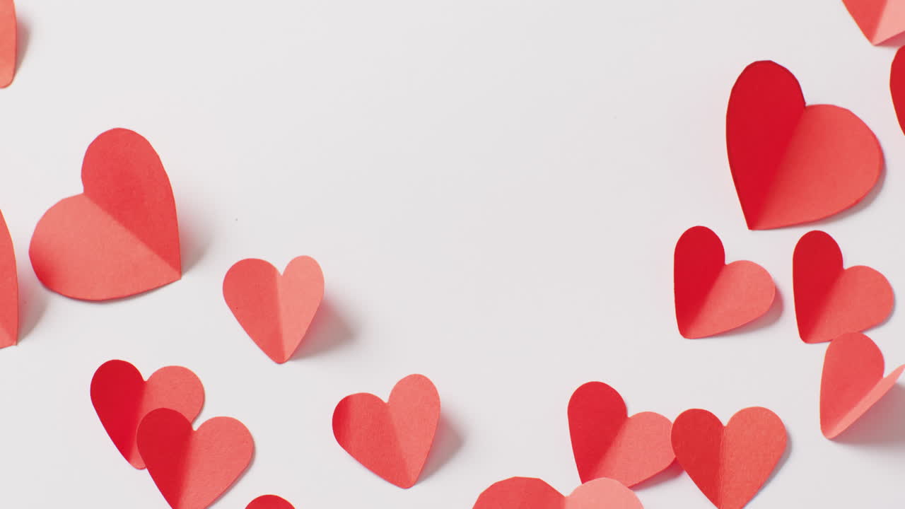 Video di forme di cuore di carta rosse piegate, su sfondo bianco con spazio per il testo