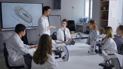 estudiantes en una clase de biología escuchando la presentación de un maestro