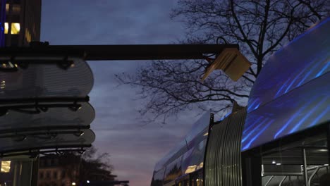 Electric-bus-departs-after-charging-at-the-bus-station---cinematic-shot