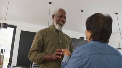 Happy-senior-diverse-couple-dancing-in-kitchen-at-retirement-home