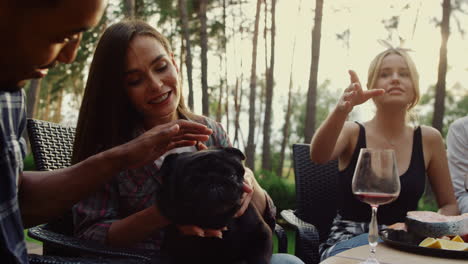 happy people having rest on grill party outside. smiling woman playing with dog