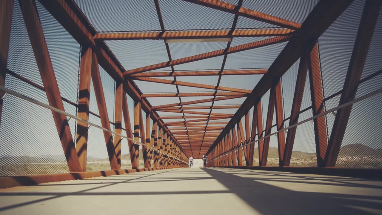 Persona che cammina su un lungo ponte metallico arrugginito nel deserto