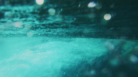 Glistening-water-texture-reveals-surfers-riding-down-in-perfect-clear-ocean