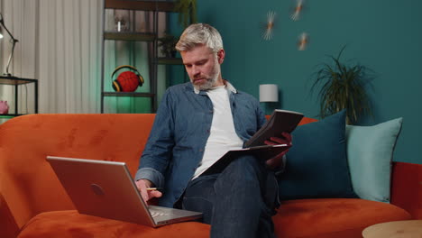 middle-aged business man working with laptop computer and documents planning expenses budget at home