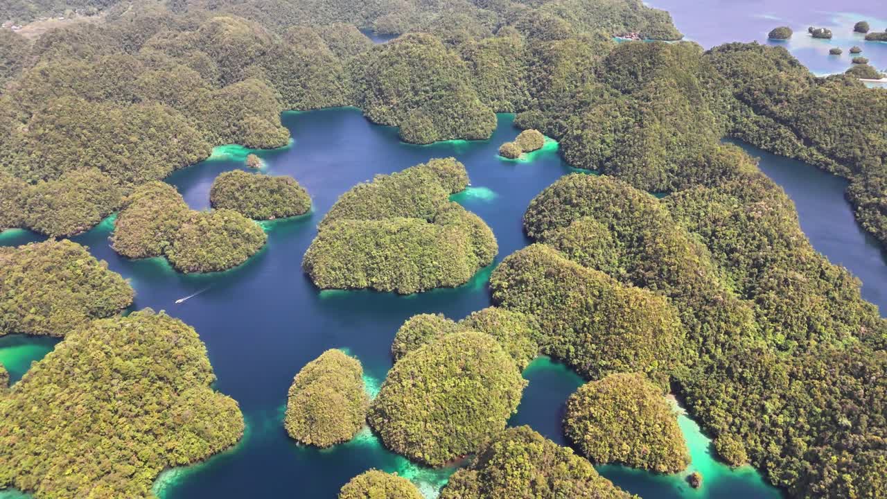 Cluster of lush limestone islets rise from clear turquoise water in Sohoton Cove National Park, Siargao, Philippines, viewed from above with visible karst topography and vibrant coastal vegetation
