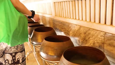 person donating coins into temple bowls