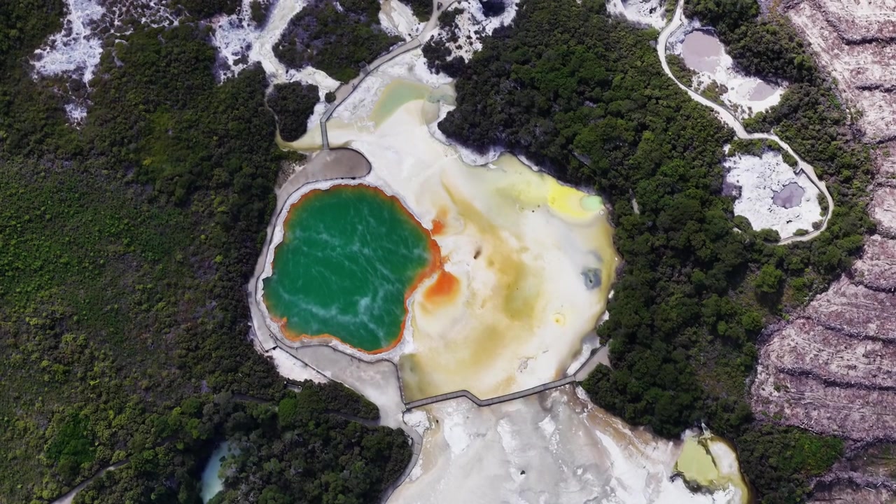 Vysokohorské dronové panorama geotermální oblasti Champagne Pool v Rotorua, Bay of Plenty, Nový Zéland, odhalující barevné termální pánve, sopečnou krajinu a okolní původní vegetaci