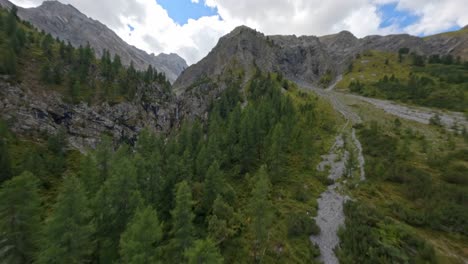 FPV-Aerial-Drone-Flying-Beside-River-Past-Waterfall-In-Davos-Switzerland-Past-Dramatic-Mountain-Landscapes