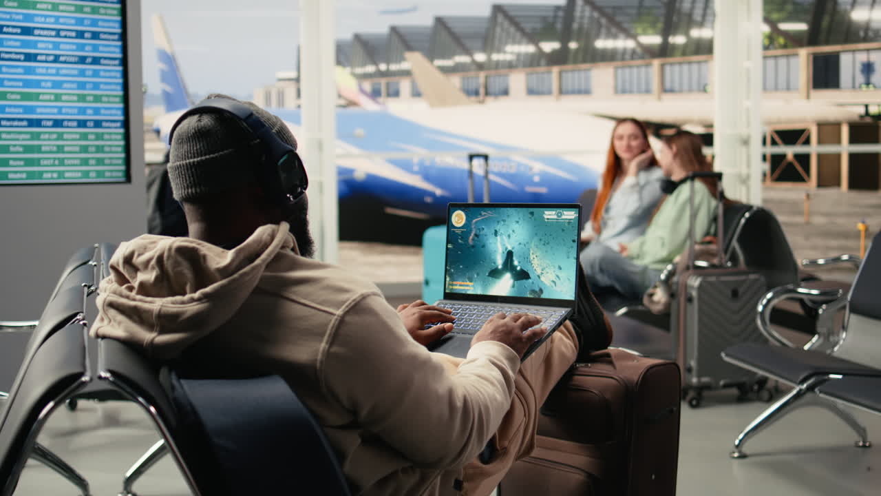 Joven gamer jugando videojuego en portátil gaming en la terminal del aeropuerto