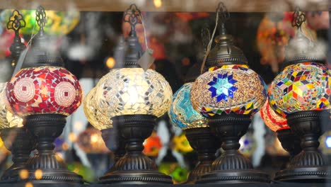 colourful turkish lamps from glass mosaic glowing. arabic multi colored authentic retro style lights. many illuminated moroccan craft lanterns. oriental islamic middle eastern decor. shiny folk shop