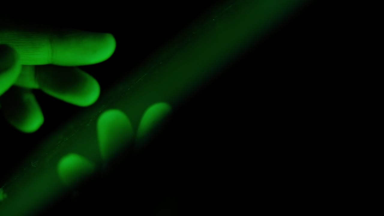 Hand touching a phone screen at night in green light