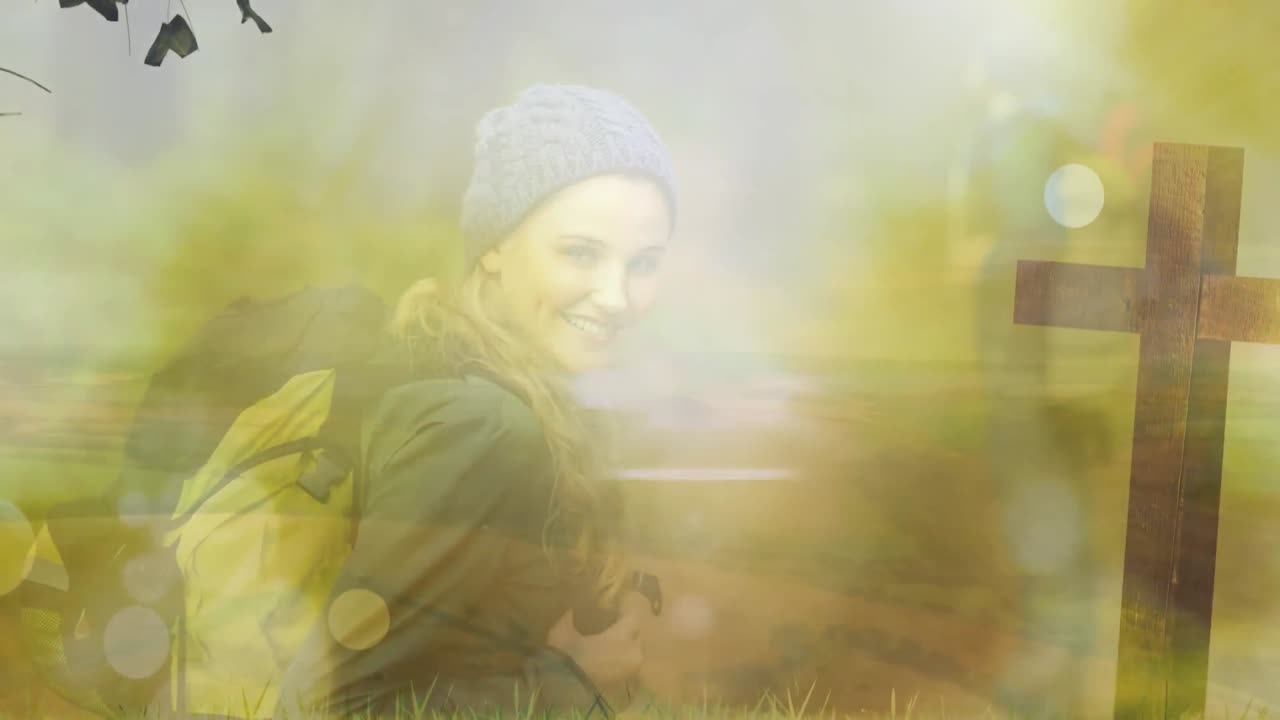 animación de una joven caucásica sonriente con mochila y cruz contra el sol brillante en el parque.