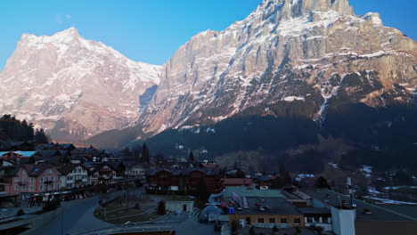 el dron asciende desde el nivel de la calle para mostrar la expansión urbana a lo largo de la base de las montañas en grindelwald, suiza.