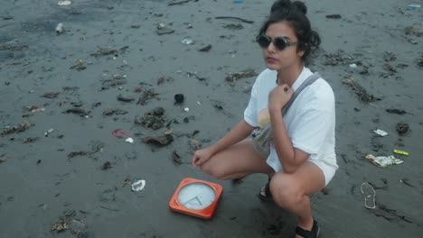 Woman-posing-on-the-beach-next-to-an-orange-clock