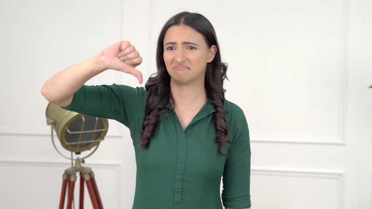 chica india mostrando los pulgares hacia abajo