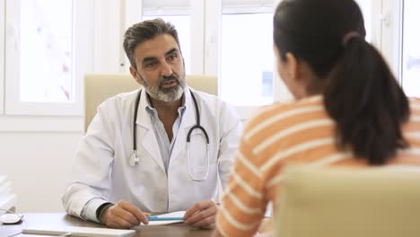 confident male doctor talking to patient in clinic during daytime