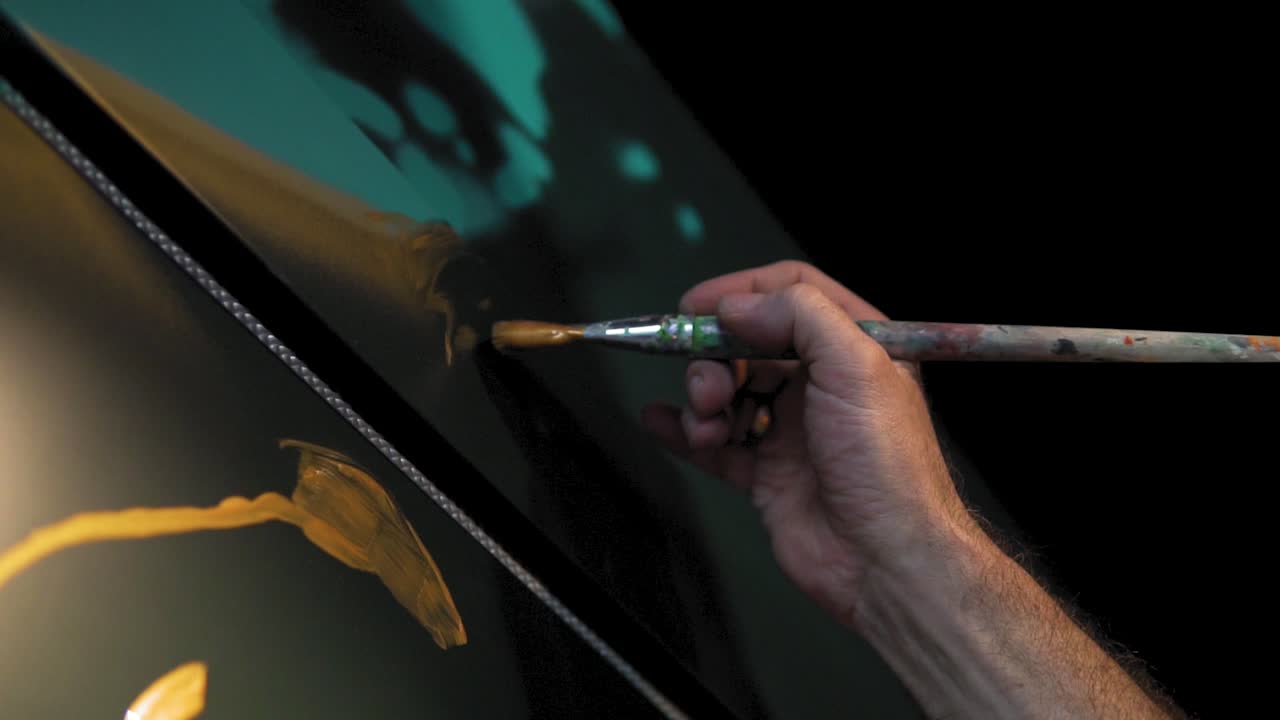 Rallentatore: la mano di un uomo sta dipingendo con un pennello durante la notte.